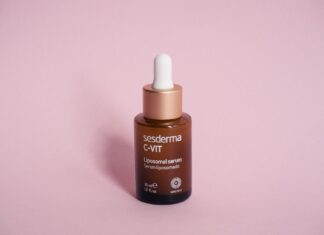 Butelka serum kosmetycznego z pipetą na różowym tle