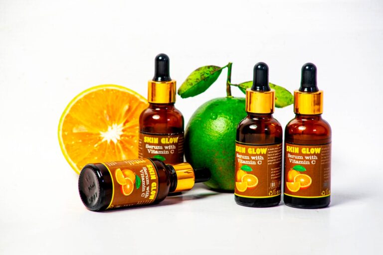 Butelki serum z witaminą C obok świeżych owoców cytrusowych